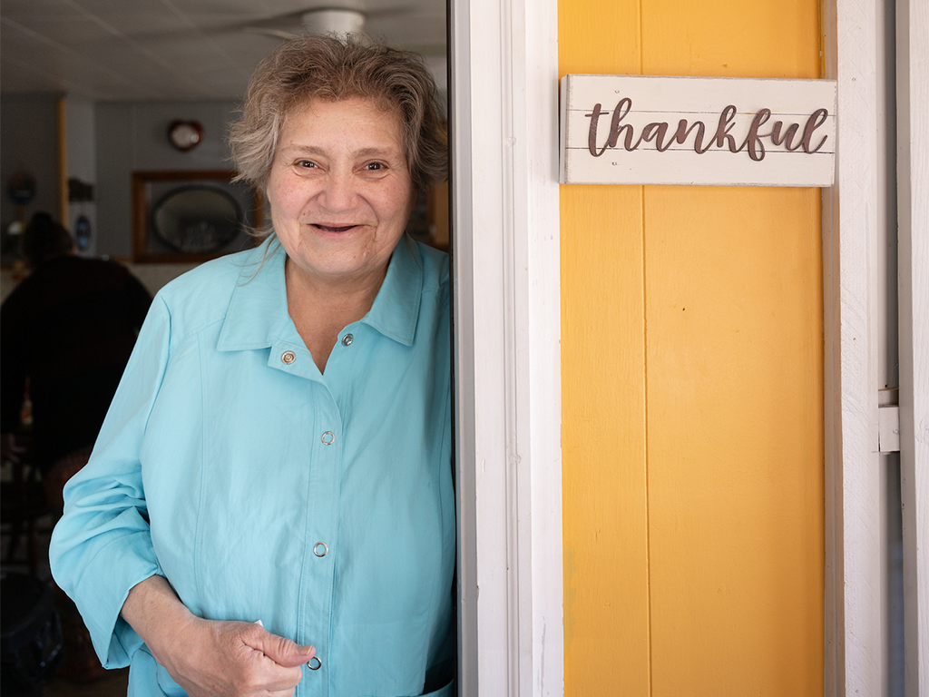 Homeowner standing in her home doorway next to a thankful time