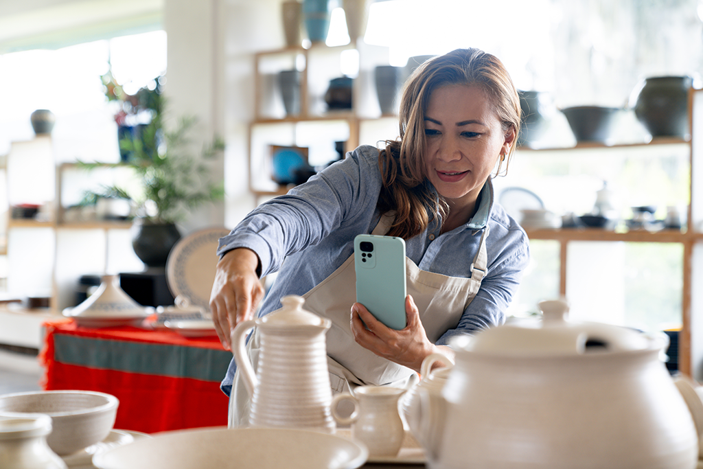 Woman business owner taking social media pictures of her inventory using a smartphone