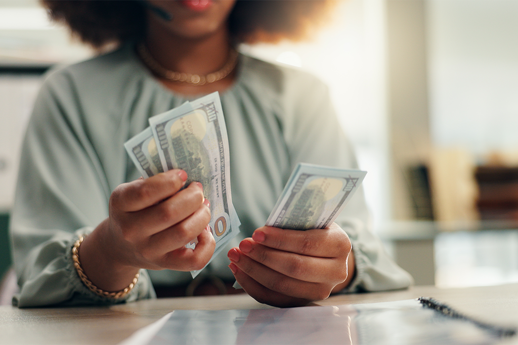 Woman business owner counting large denominations of money