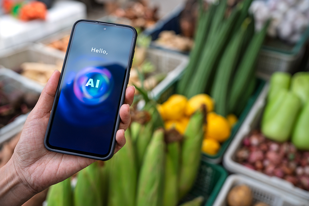 A hand holding a smartphone with AI in front of vegetables