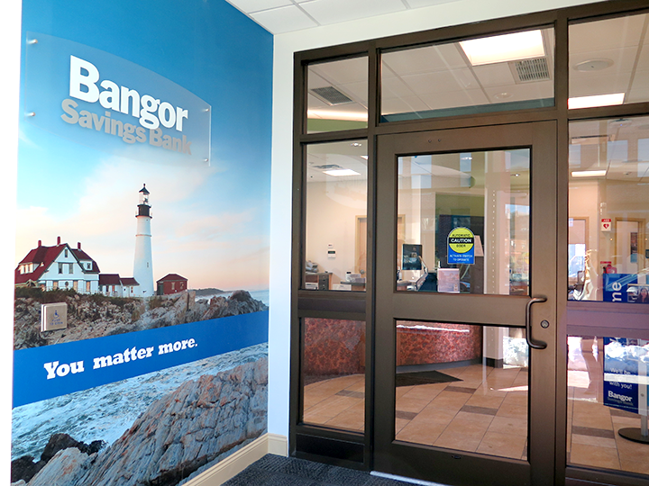 Entrance doors inside the Bangor Savings Bank branch at 77 Middle Street in Portland, Maine, with branded wall mural nearby